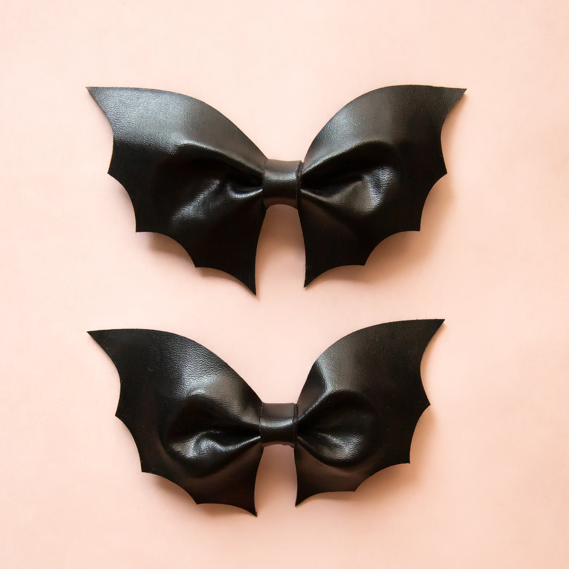 Two bat shaped black leather hair bows