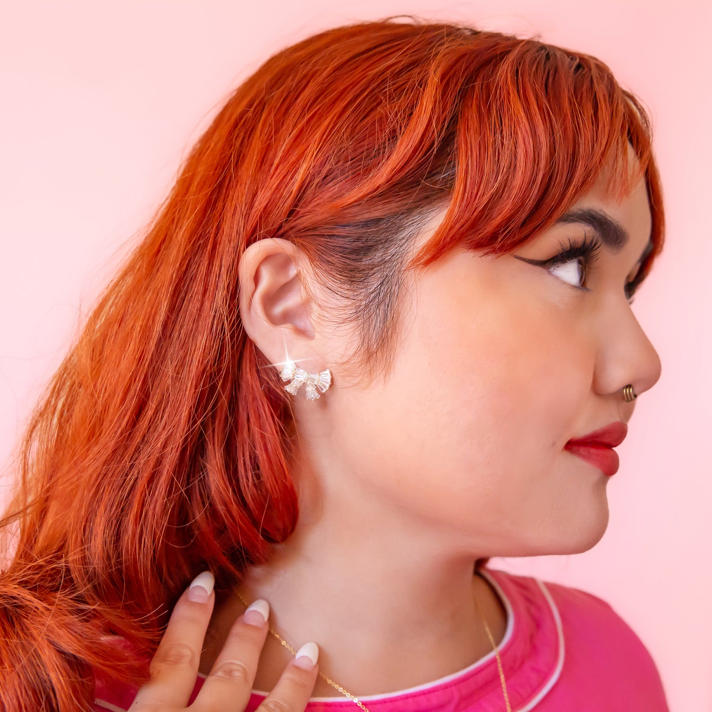 A model wearing bow shaped stud earrings.