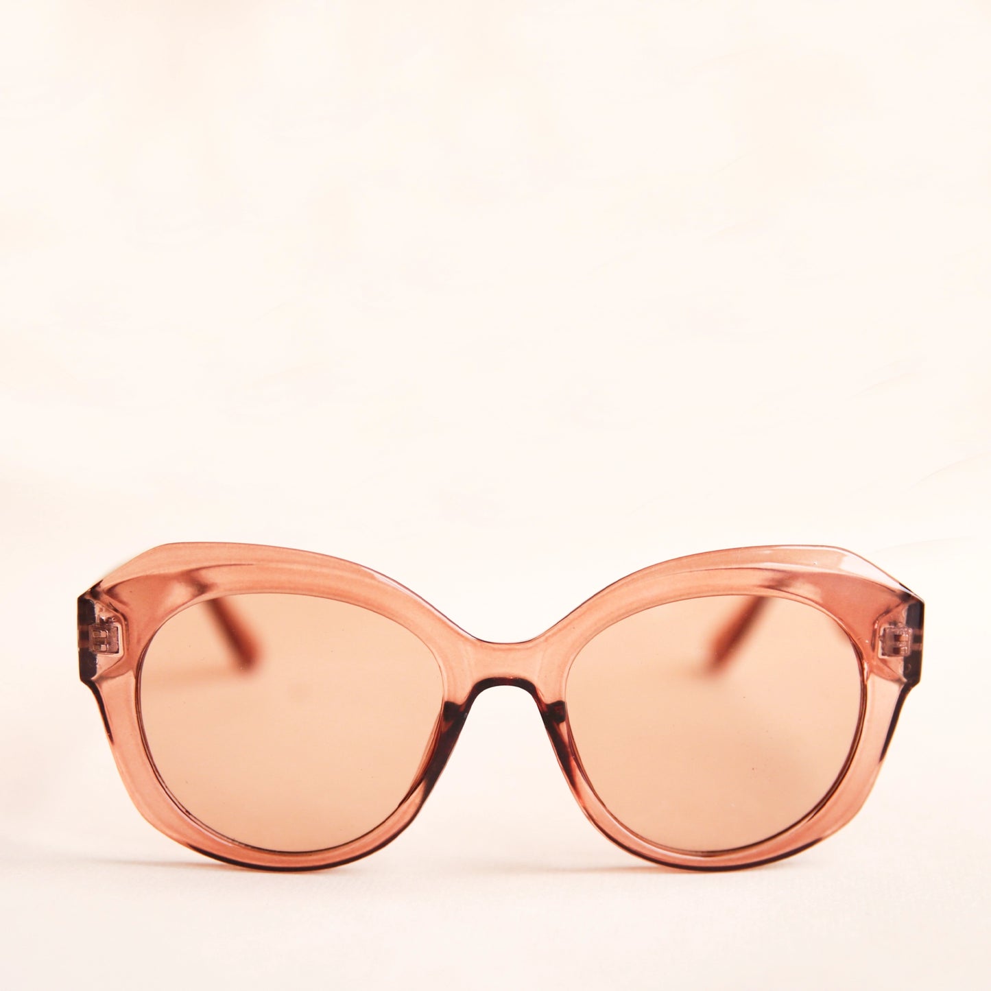 On a white background is a light brown translucent sunglasses that have a rounded shape and a light brown lens.