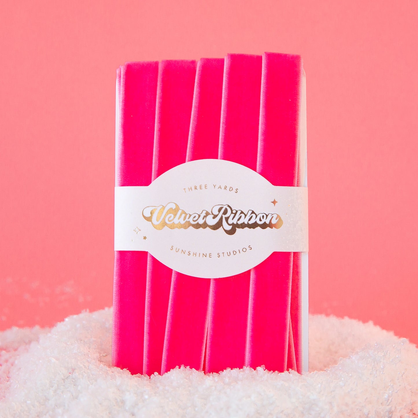 On a pink background is a spool of velvet pink ribbon.