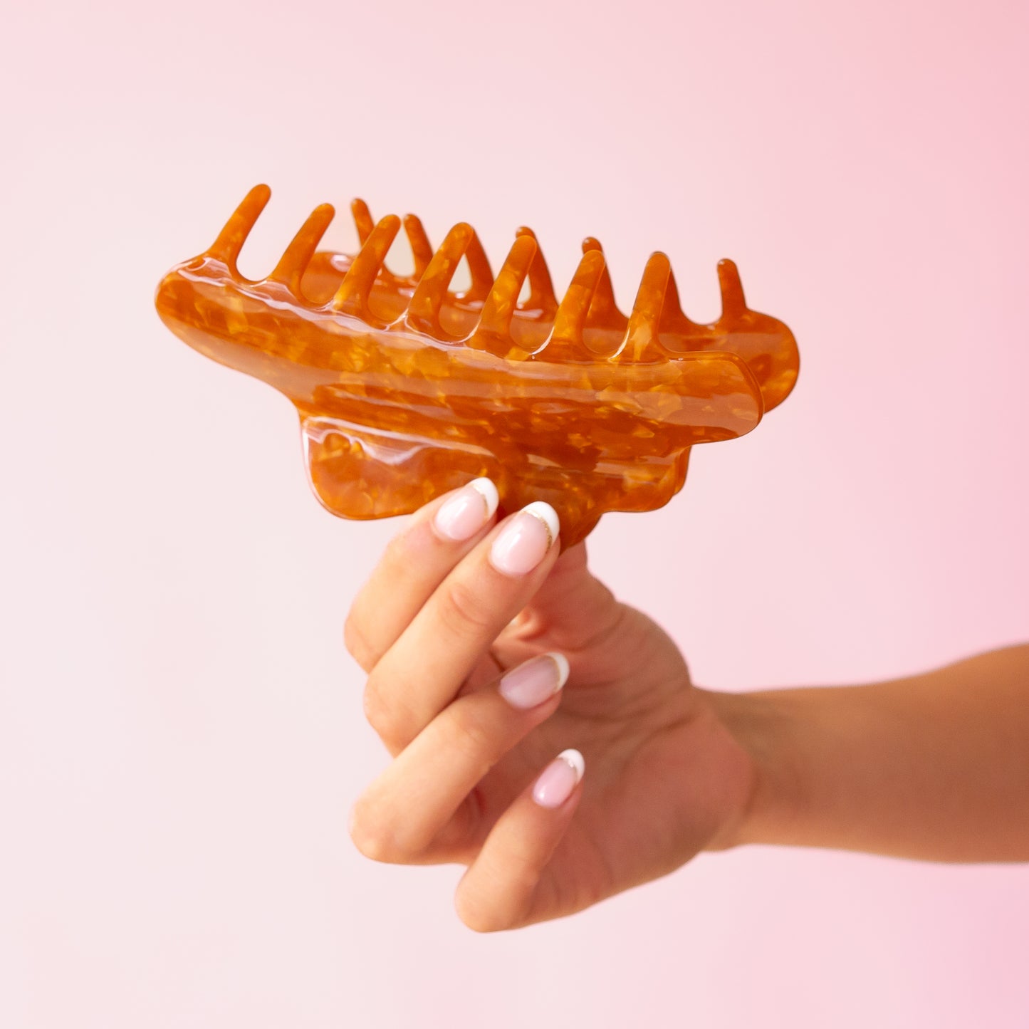 A brown acetate hair claw clip with a wavy rounded edge.
