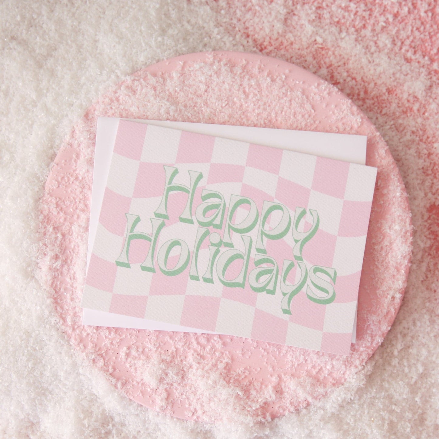 A pink and white checkered card with green and ivory text that reads, "Happy Holidays".