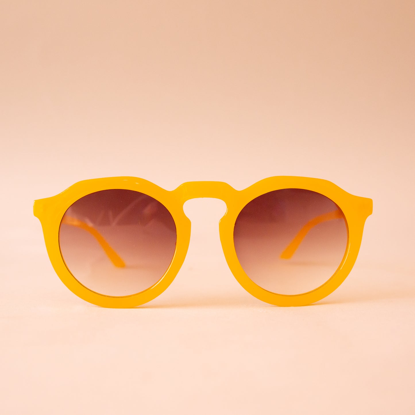 A pair of yellow round sunglasses with a brown gradient lens.