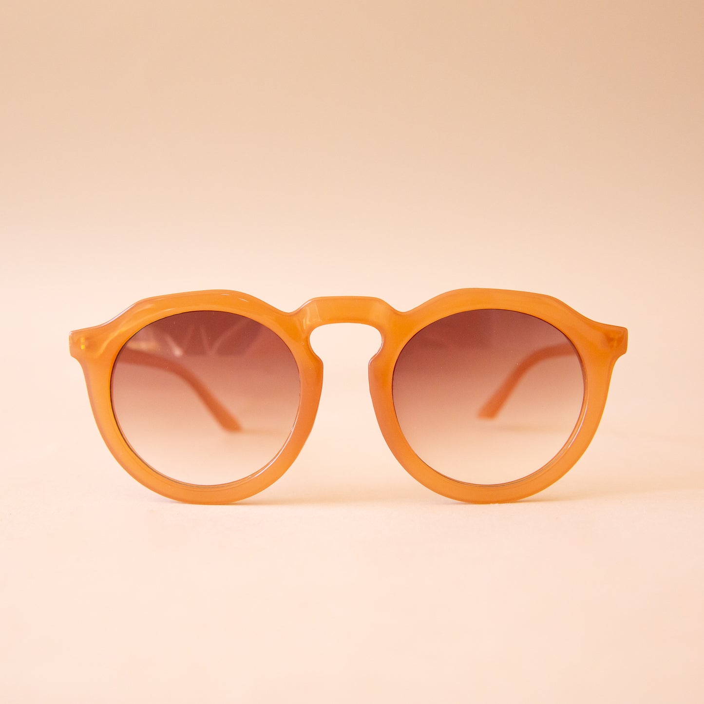 A warm brown pair of round sunglasses with a brown gradient lens.