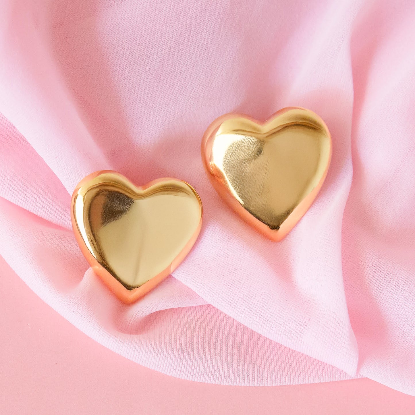 A pair of gold heart shaped earrings.