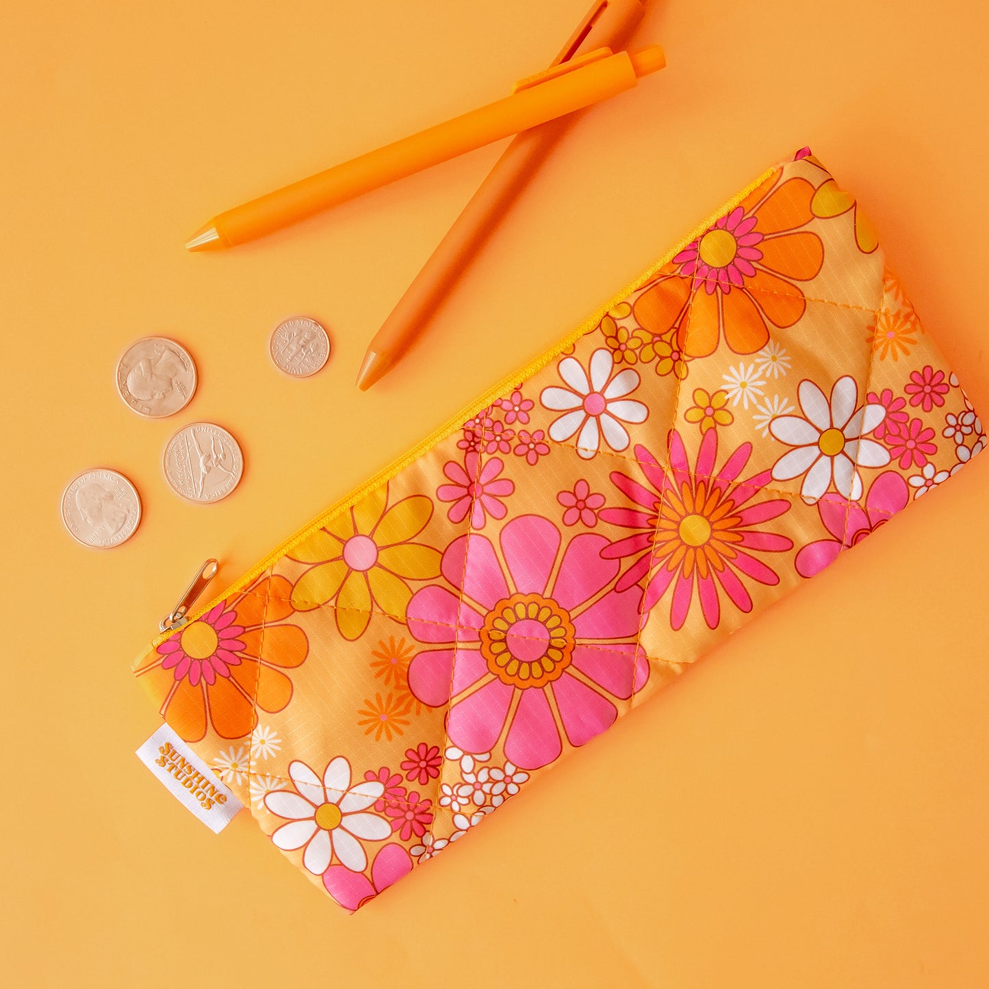 A floral print pencil pouch in orange, pink and ivory tones.