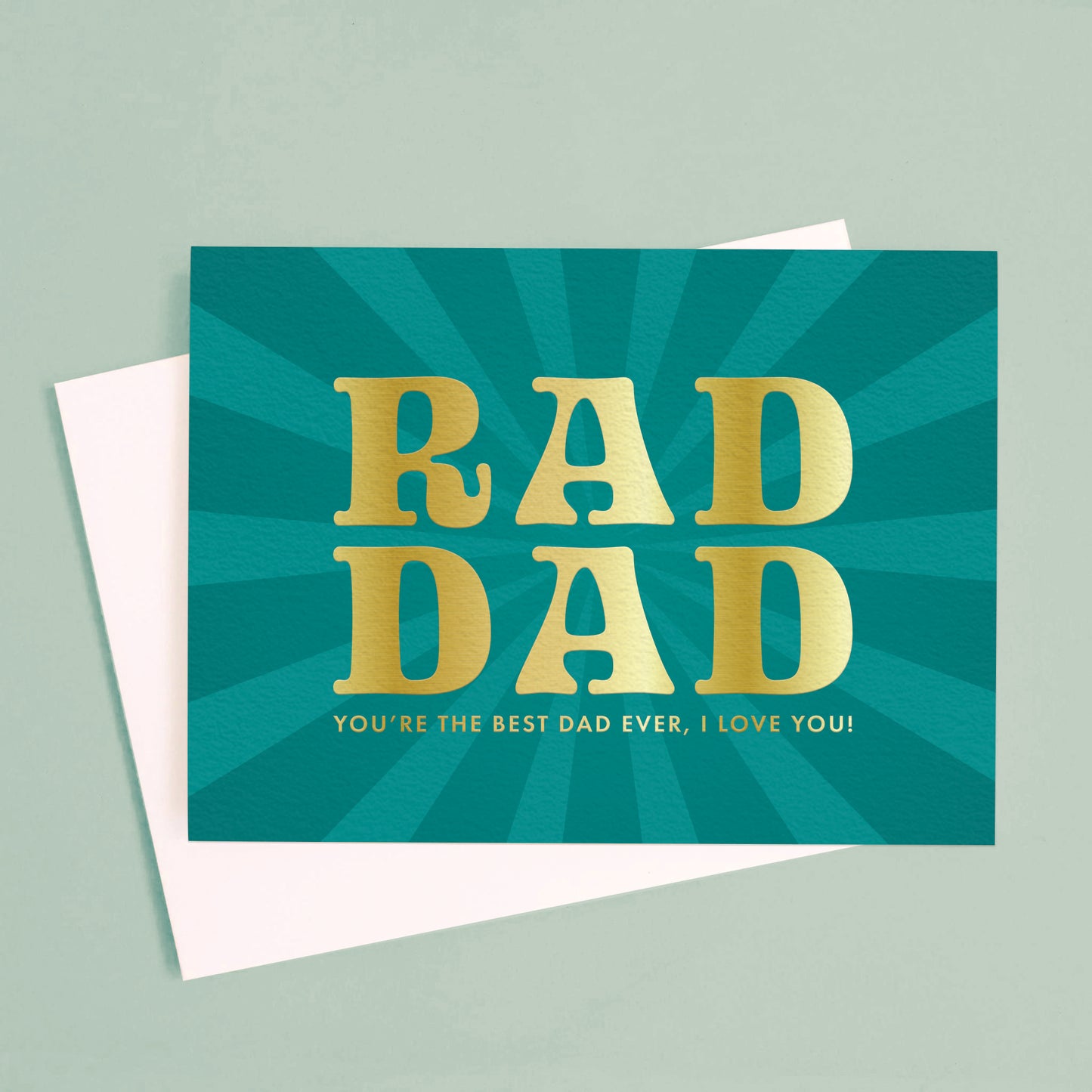 On a green background is a blue teal card with gold text that reads, "Rad Dad You're The Best Dad Ever, I Love You".