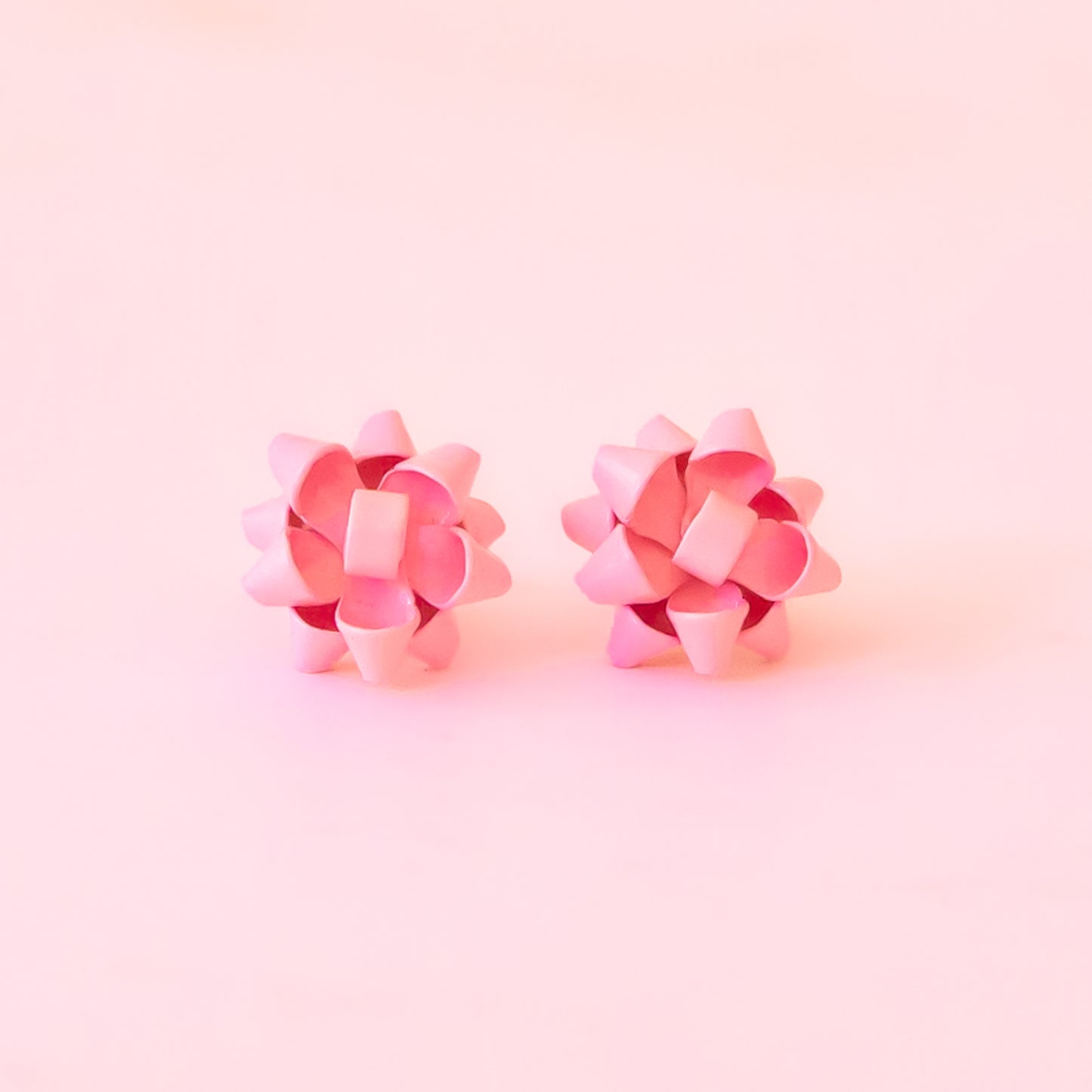 A pink pair of bow shaped earrings.