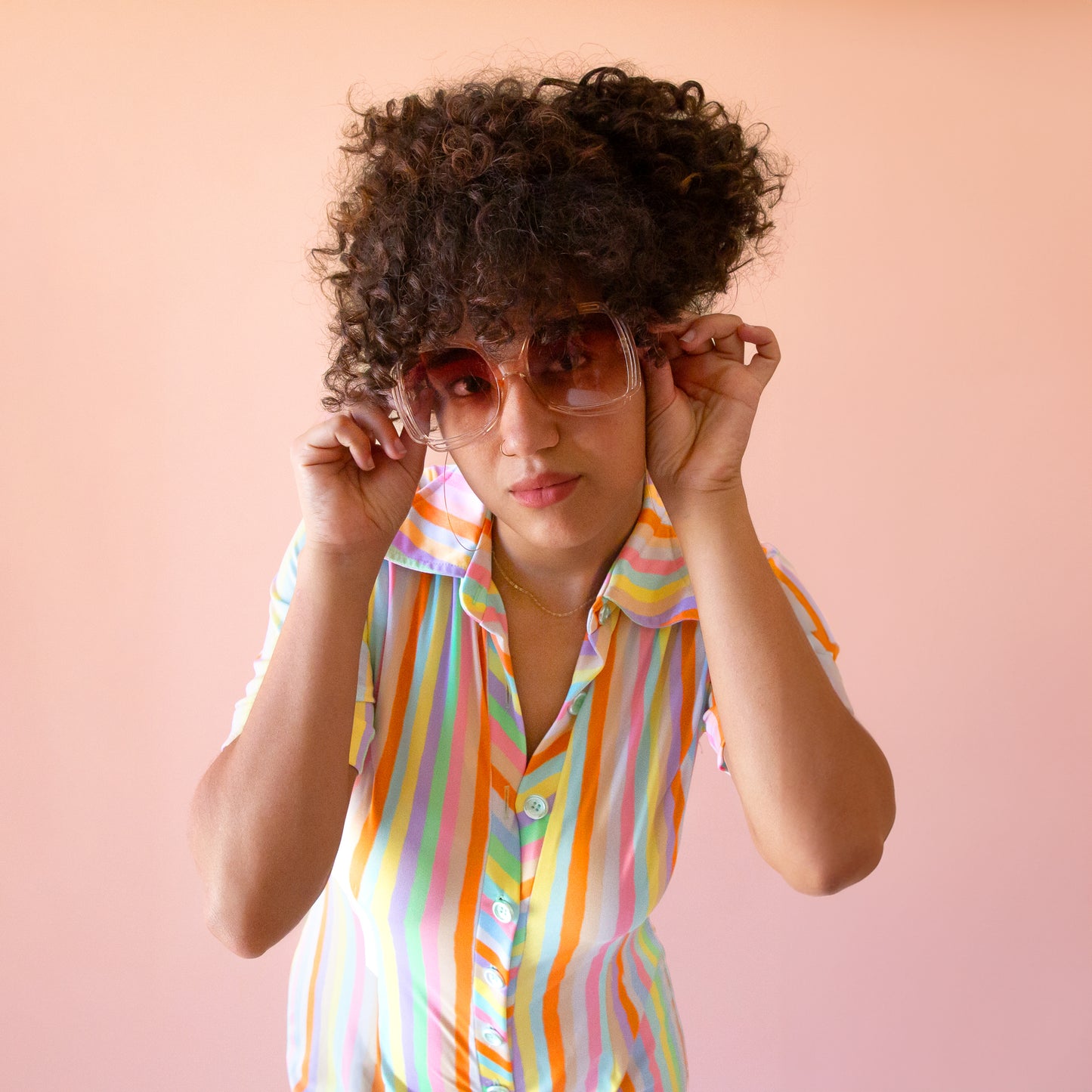 A pair of sunglasses with a clear peachy frame and pinkish gradient lenses.