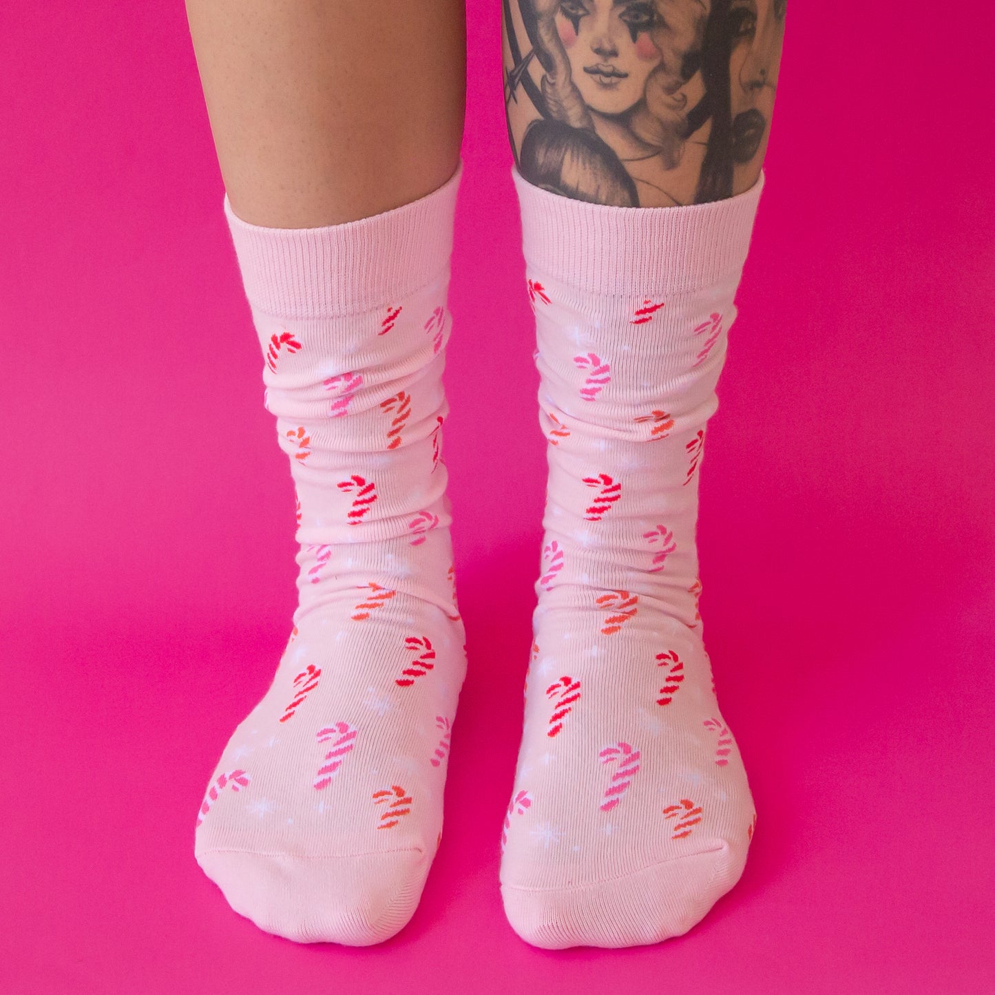 A pair of pink crew socks with a pink candy cane pattern.