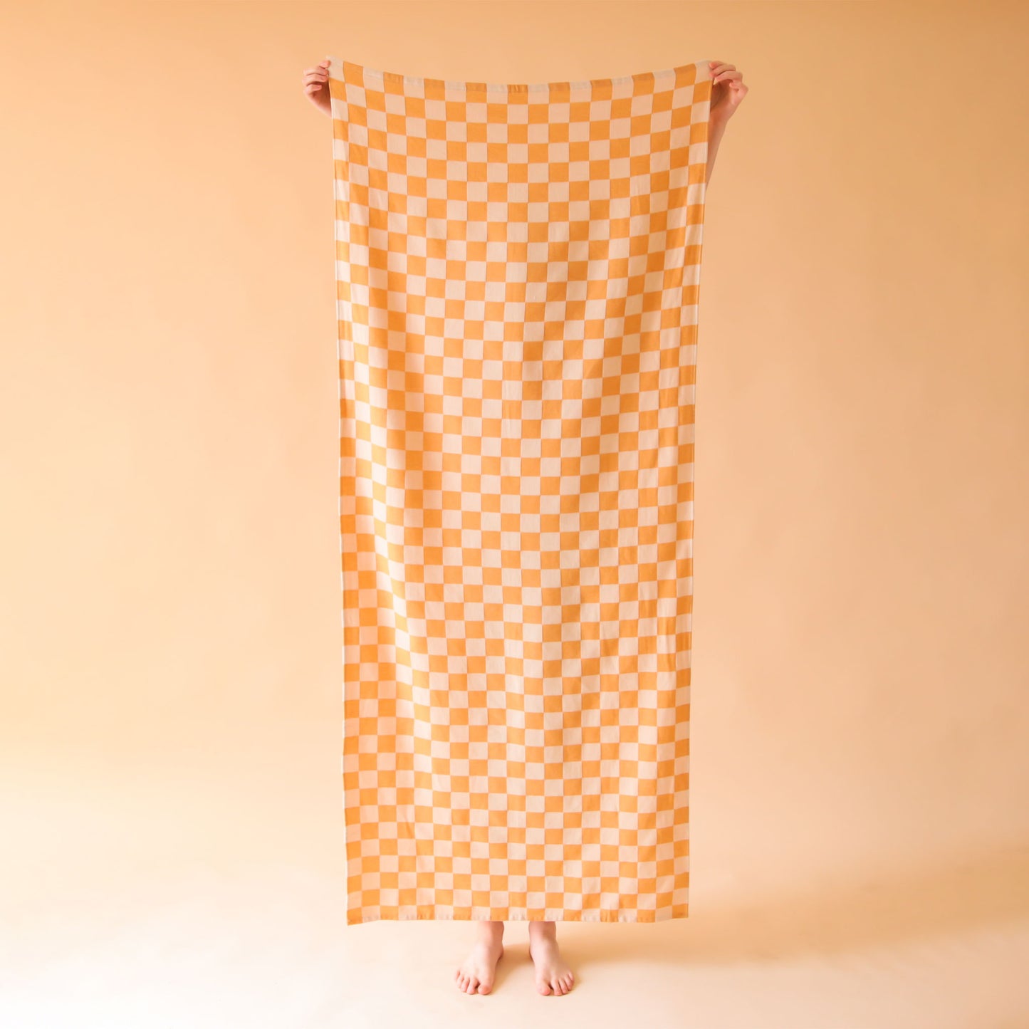 On a tan background is an orange and and light orange beach towel.