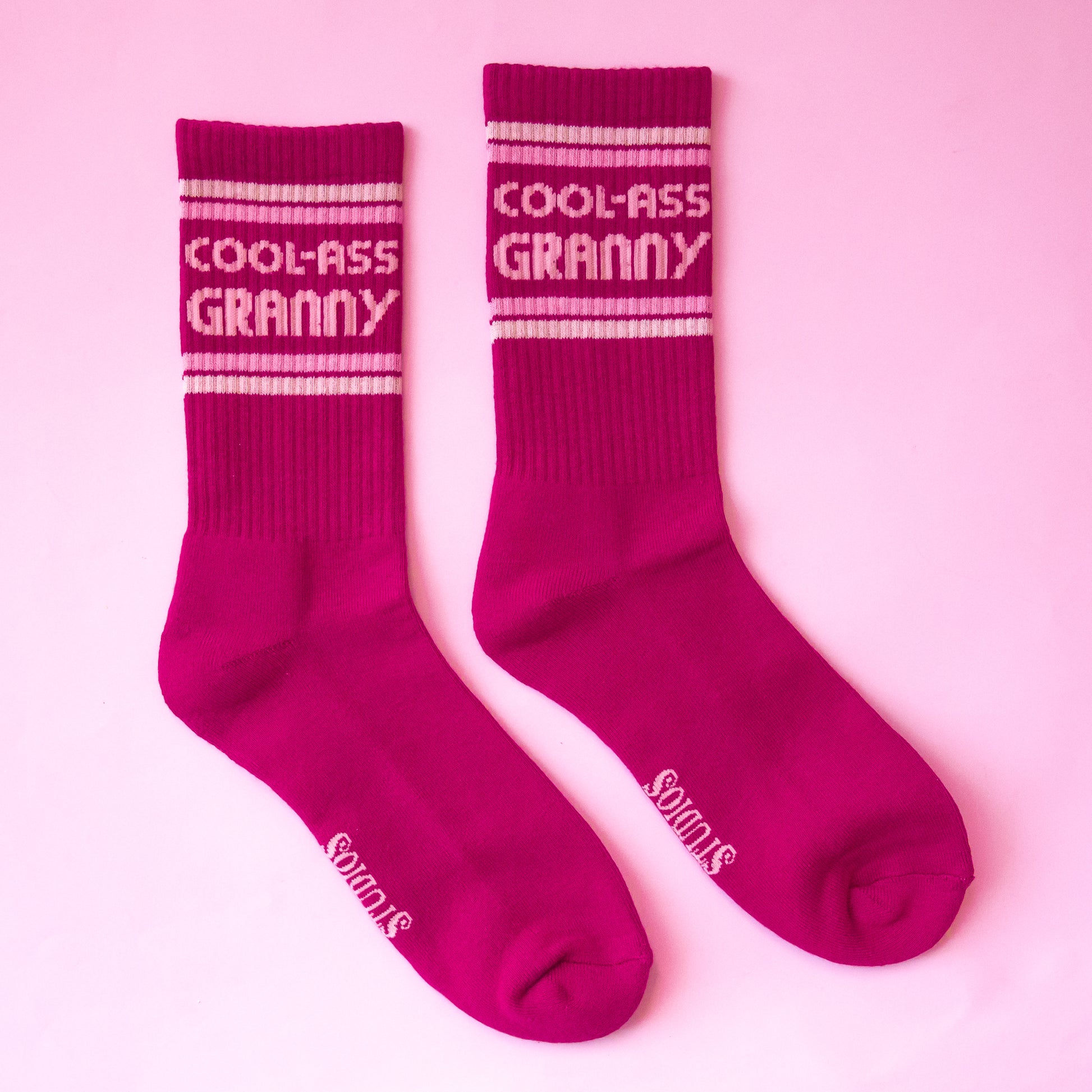 Dark pink ribbed crew socks that read, 'Cool-Ass Granny' on the ankle of the socks in light pink letters.