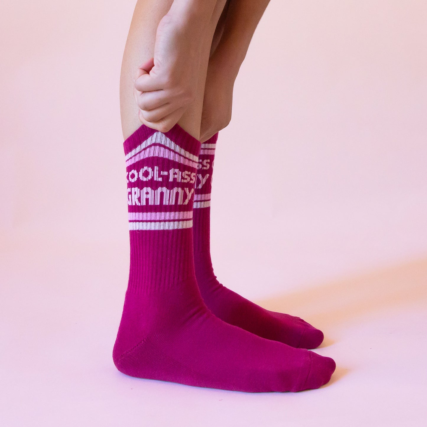 Dark pink ribbed crew socks that read, 'Cool-Ass Granny' on the ankle of the socks in light pink letters.