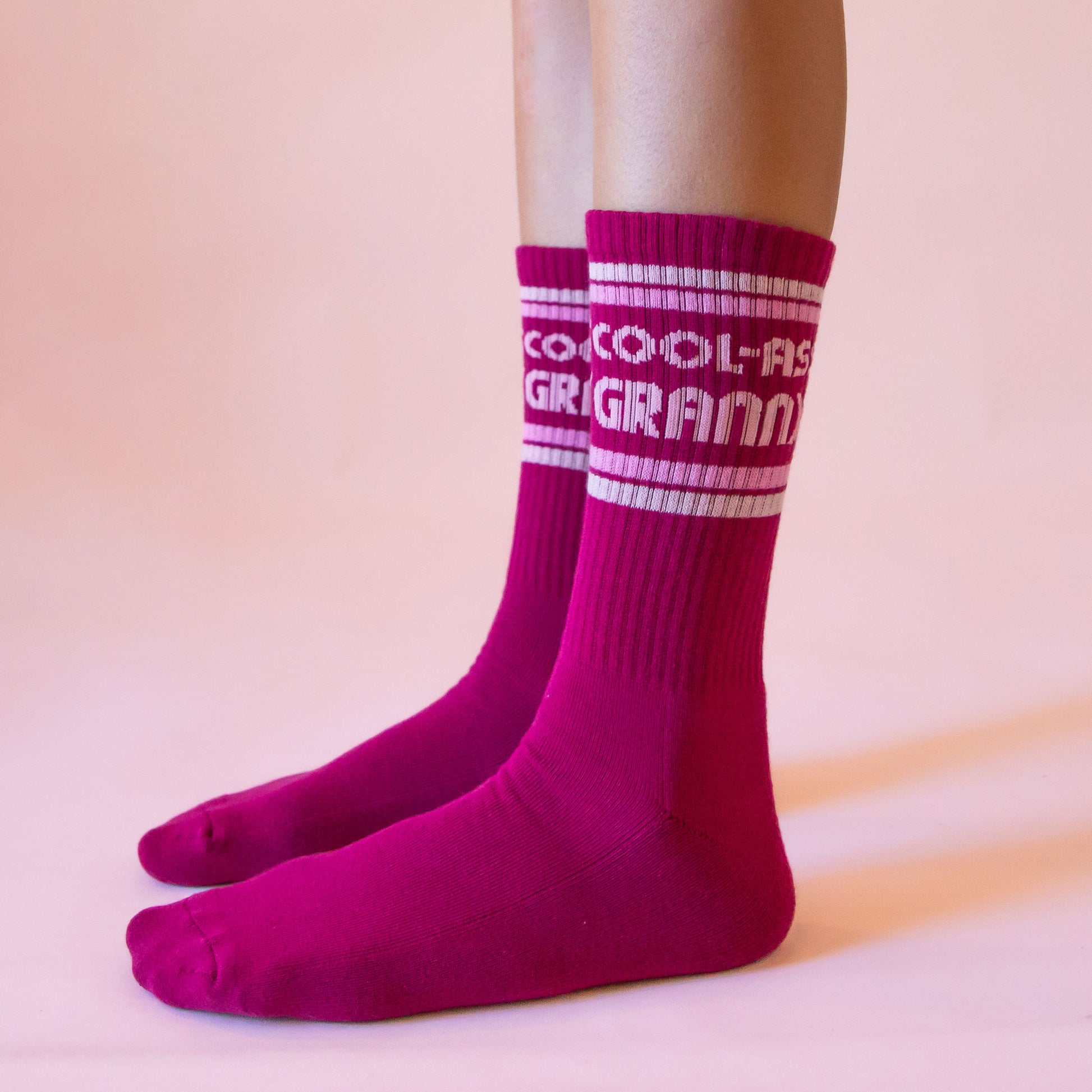 Dark pink ribbed crew socks that read, 'Cool-Ass Granny' on the ankle of the socks in light pink letters.