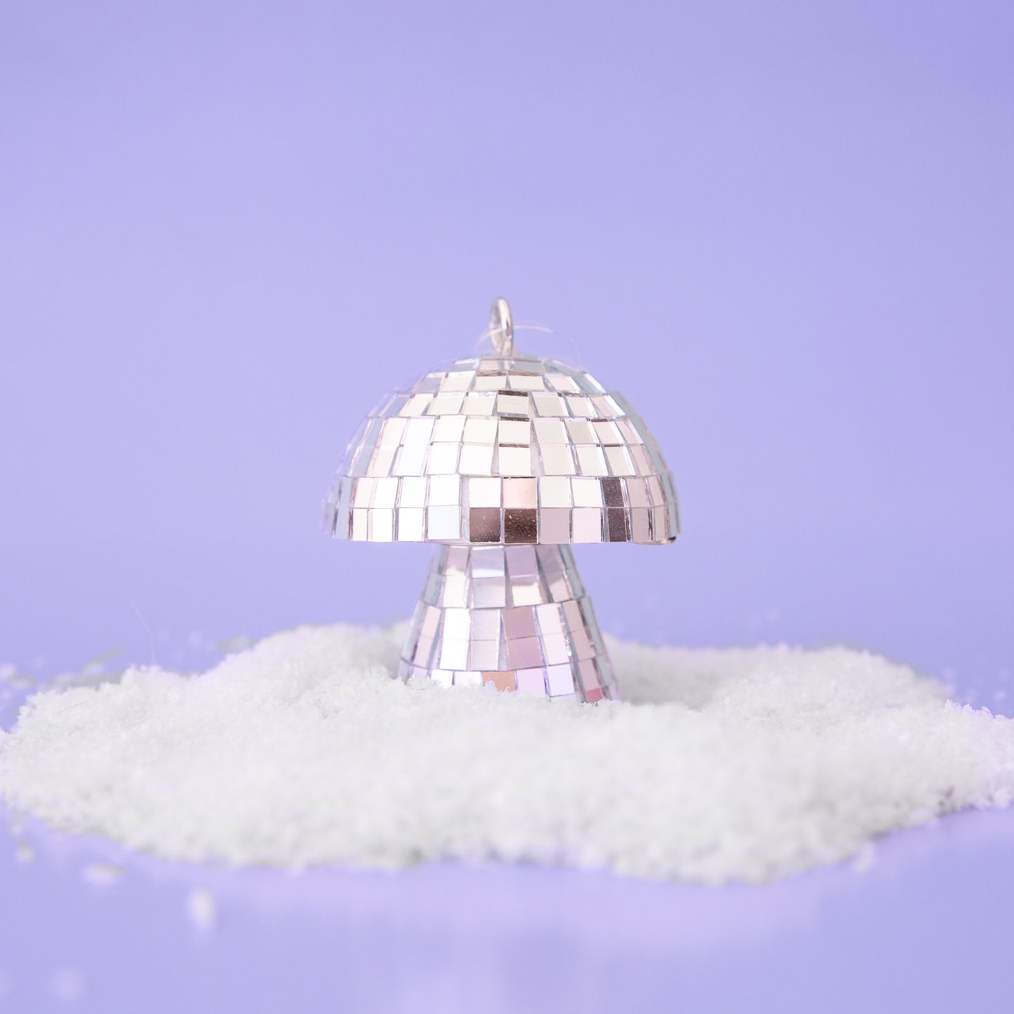On a purple snowy background is a silver disco mushroom ornament.