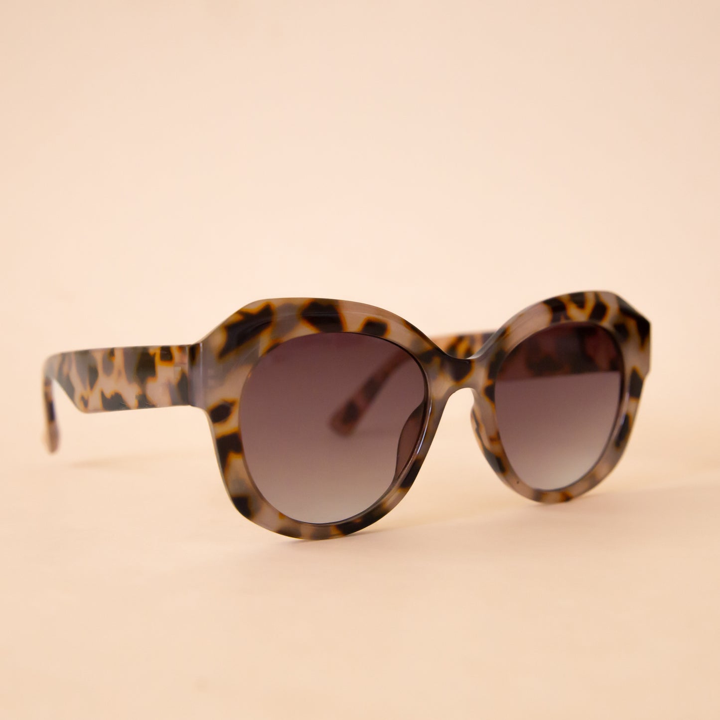A pair of leopard brown and black sunglasses with a rounded shape.