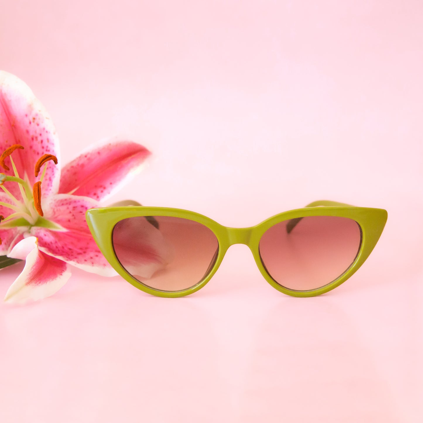 A green pair of cat-eye shaped sunglasses with a brown lens.