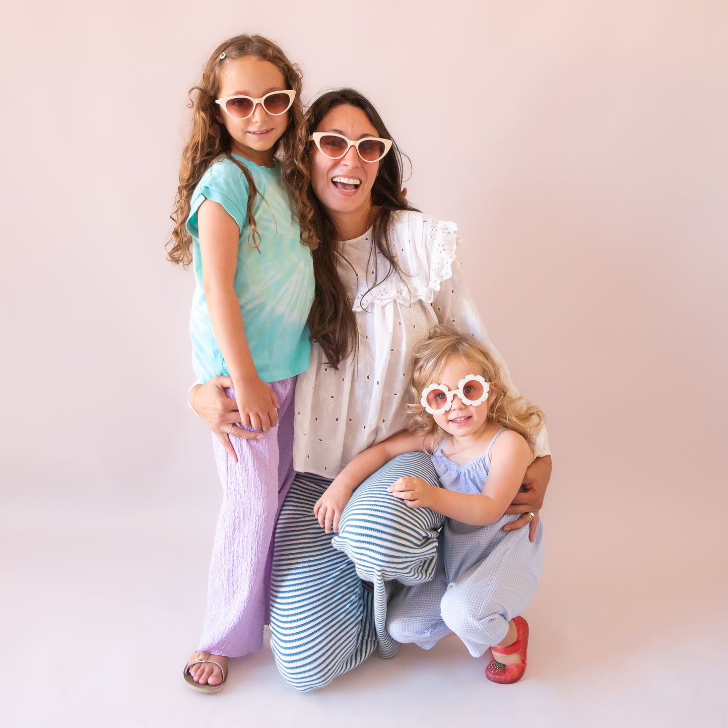 A mom and two daughters wearing the Frenchie sunglasses in the shade ivory in the adult and children's size.