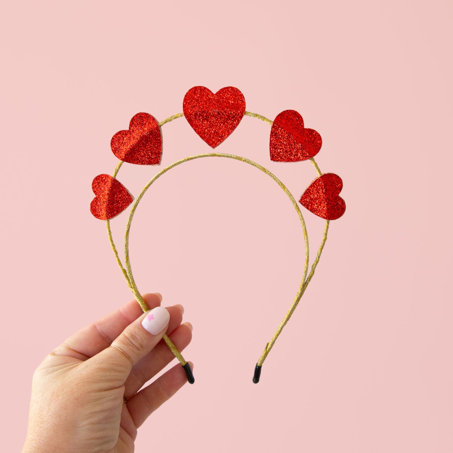 A headband hair accessory with red glitter hearts along the top.