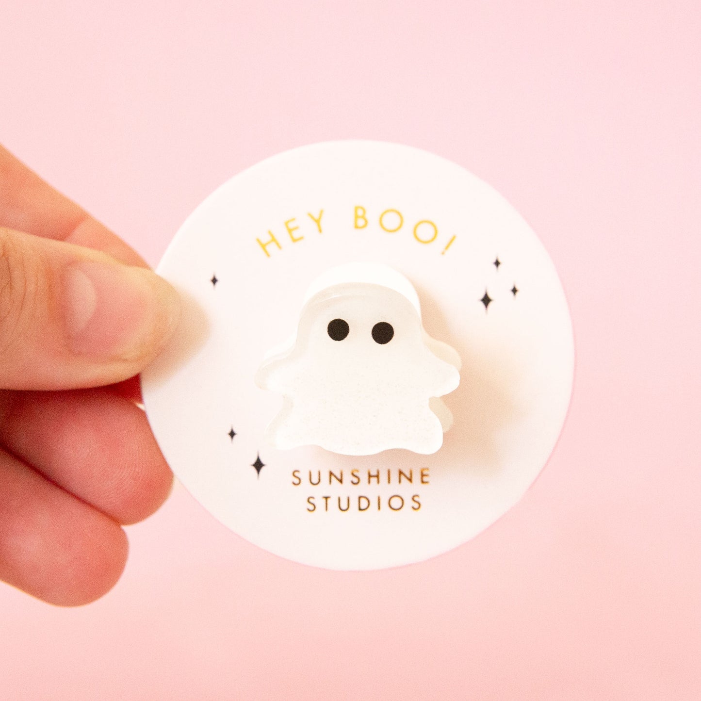A ghost shaped hair clip on a round white tag that reads, "Hey Boo!"