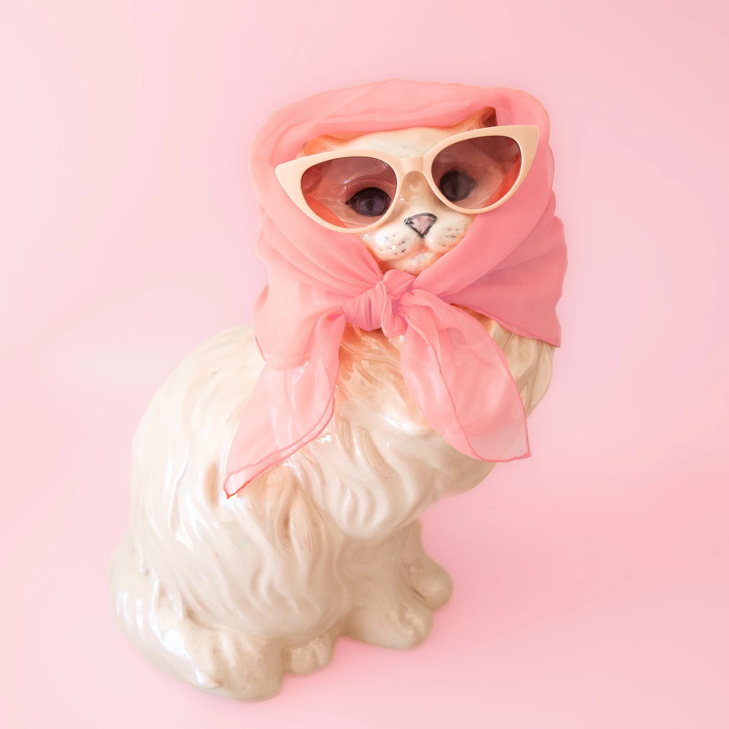 An ivory pair of cat-eye shaped sunglasses with a brown lens.