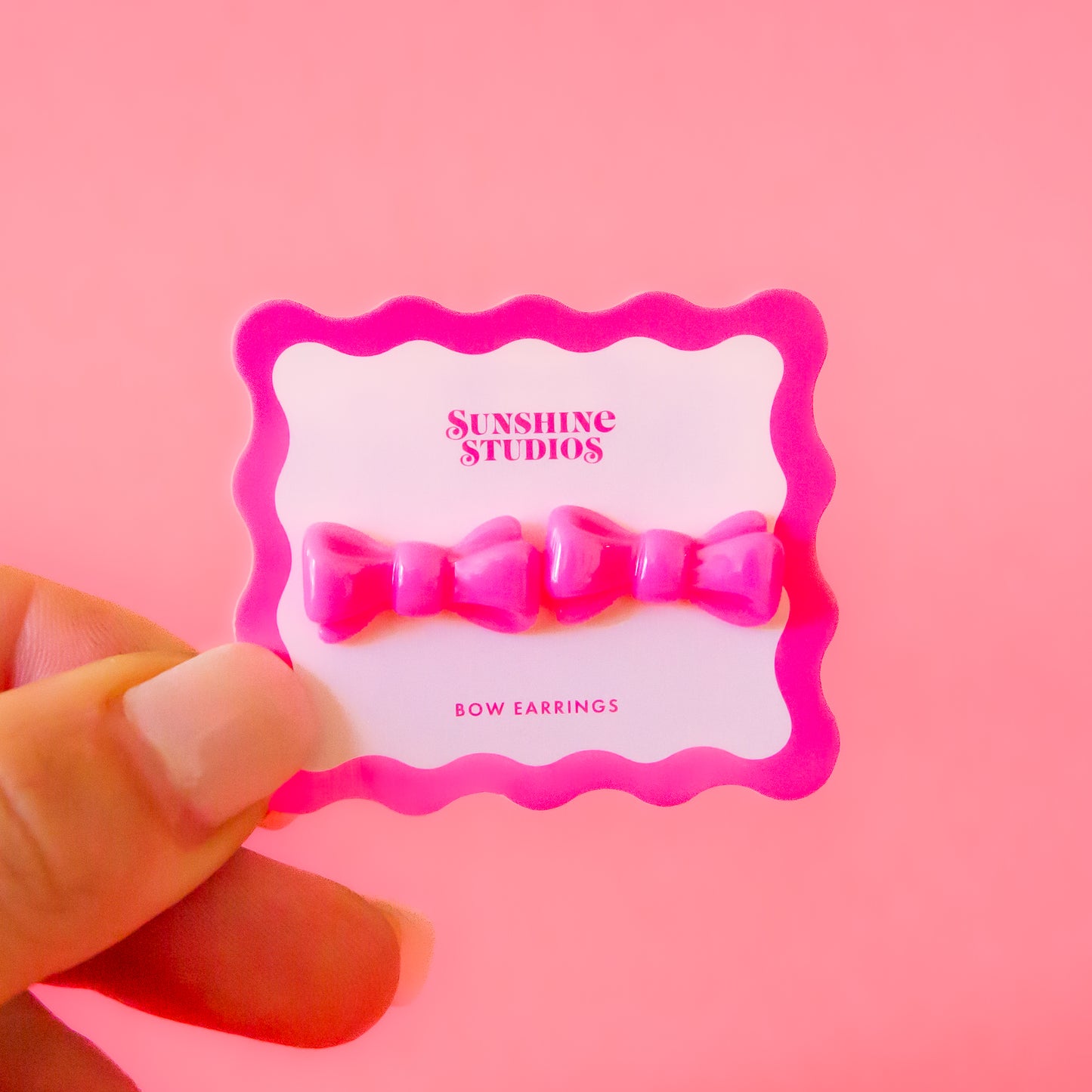 A pair of pink bow shaped earrings.