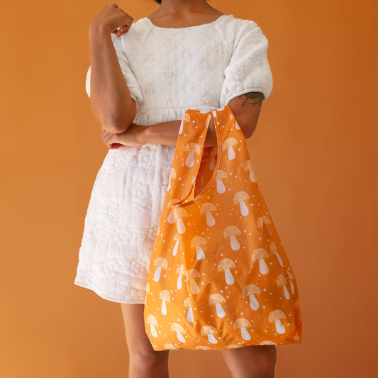 An orange nylon bag with a mushroom and twinkle star print. 