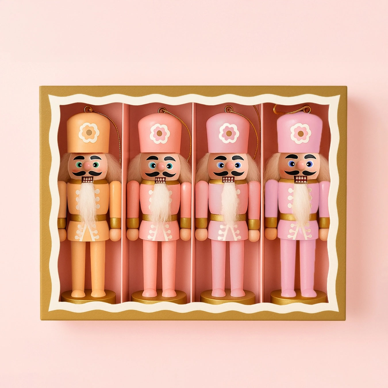 A set of four nutcracker ornaments in a variation of orange and pink tones with flowers on their hats.