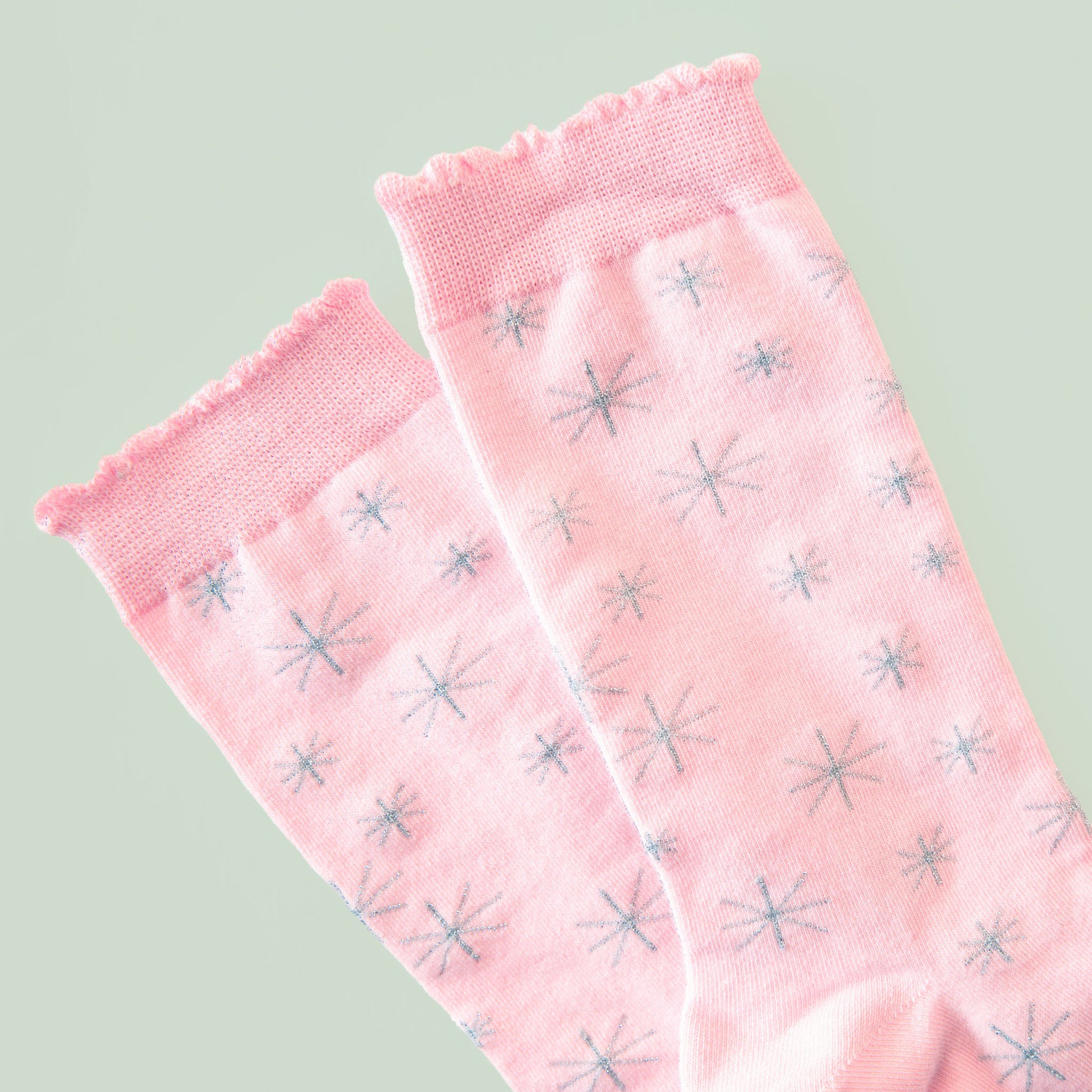 A pair of light pink socks with a silver star pattern.