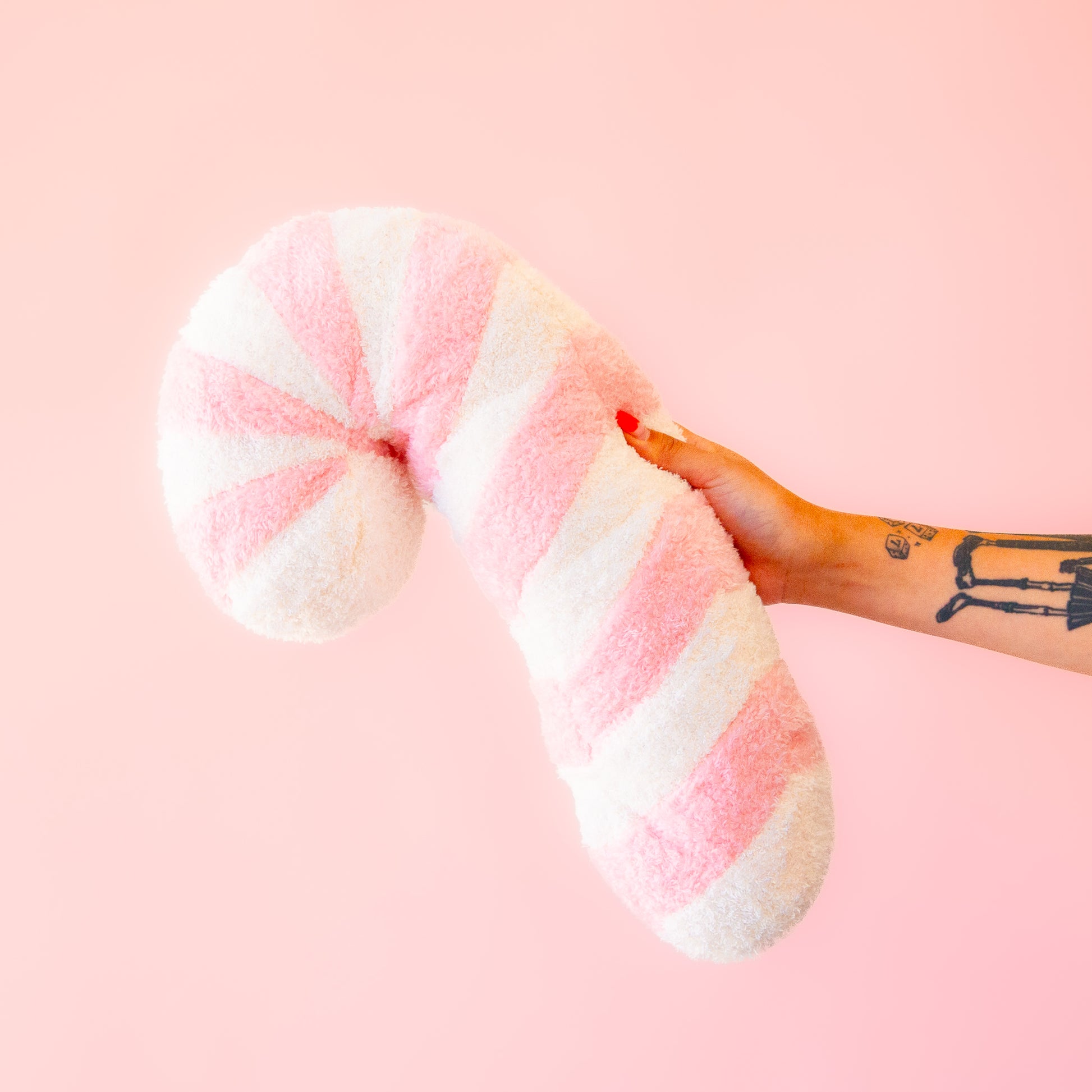 A light pink and white striped candy cane shaped pillow.