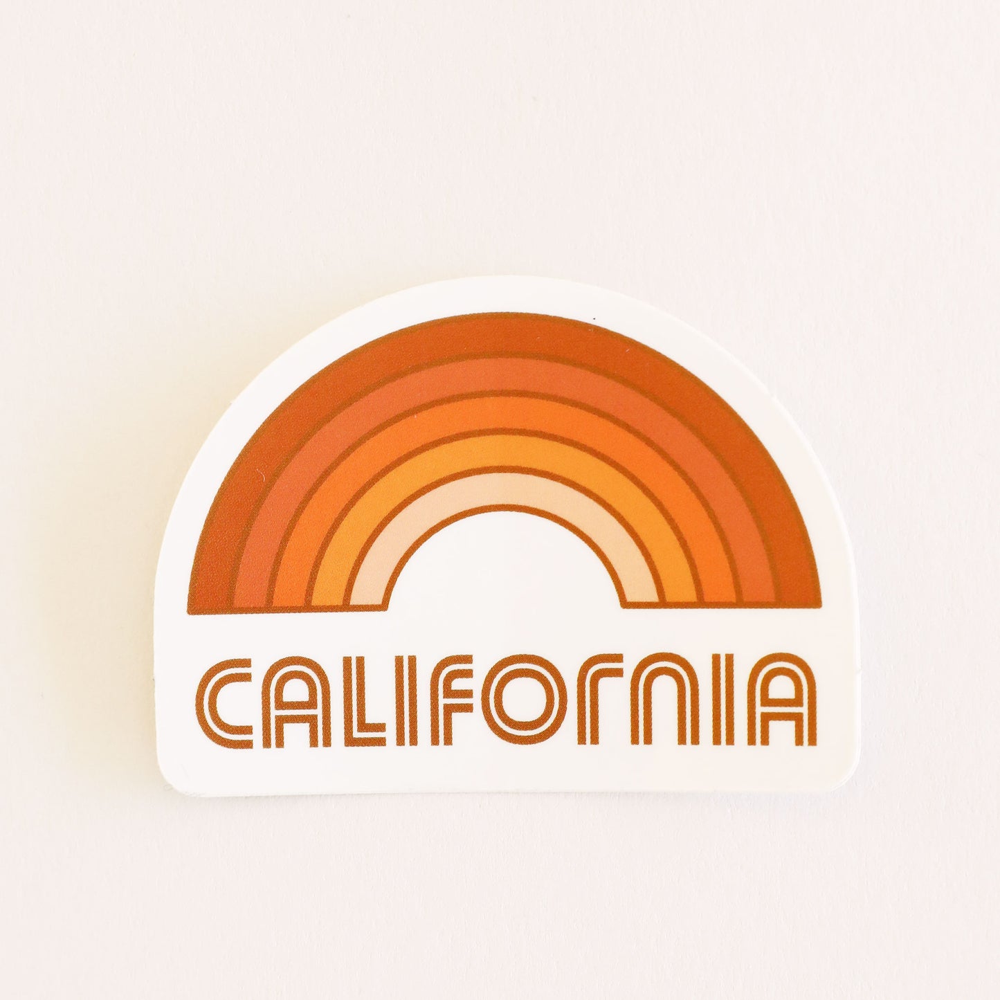 A rainbow sticker made up of different shades of orange and "California" written in orange letters on the bottom underneath the rainbow graphic.