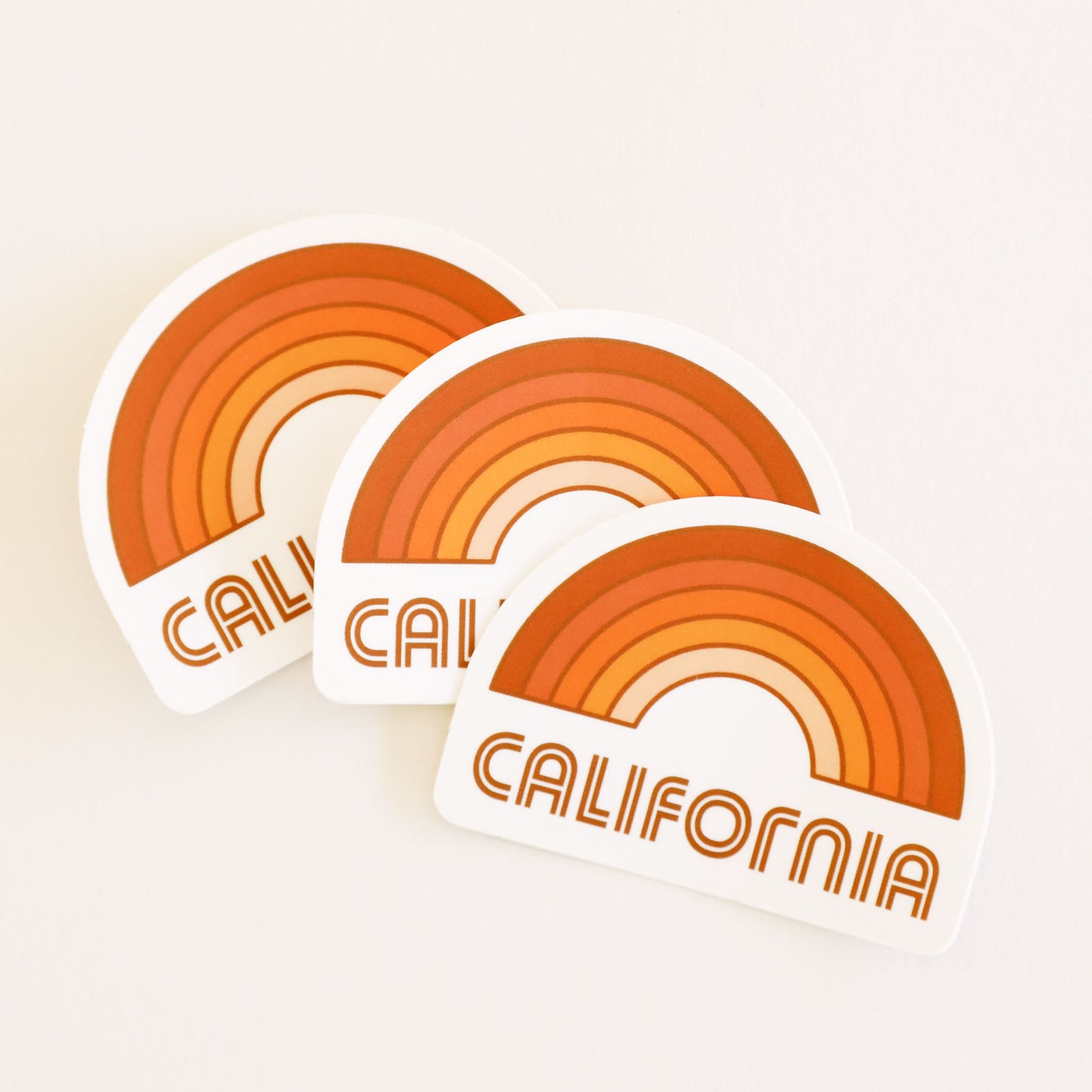 A rainbow sticker made up of different shades of orange and "California" written in orange letters on the bottom underneath the rainbow graphic.