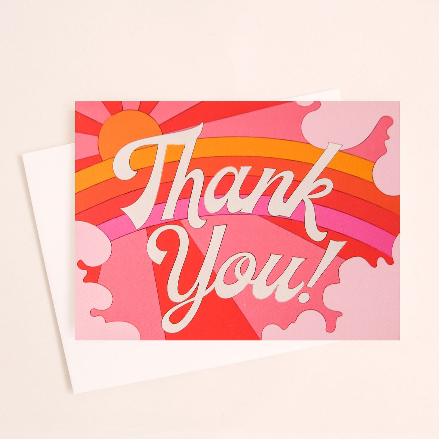 Card with a vibrant scene of a rosie toned rainbow and beaming pink and red sun. Soft pink cloud take up the edges. The center of the card reads 'Thank you!' in white cursive lettering.