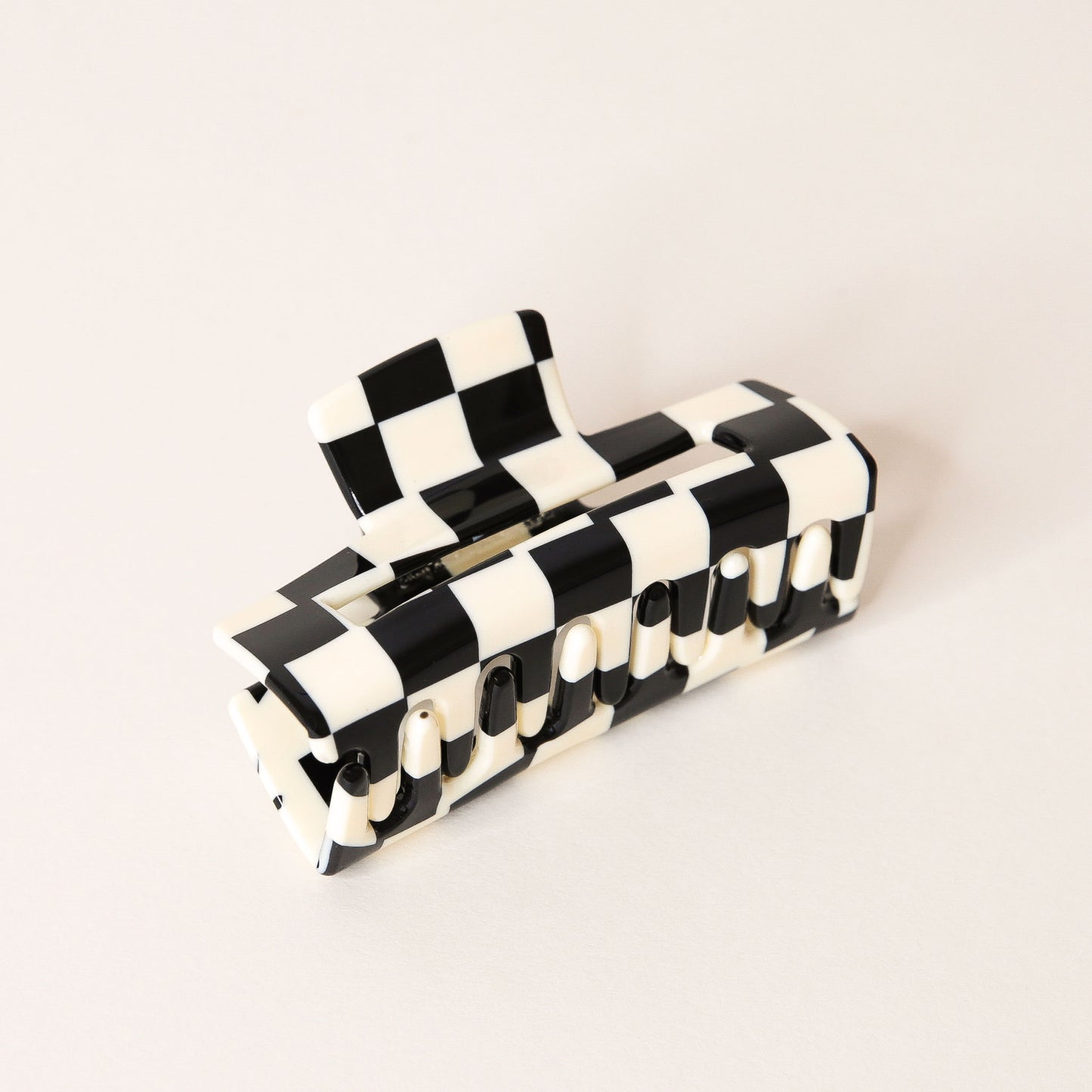 Large black and white checkered claw hair clip with a narrow rectangle shape and two simple geometric cutouts.