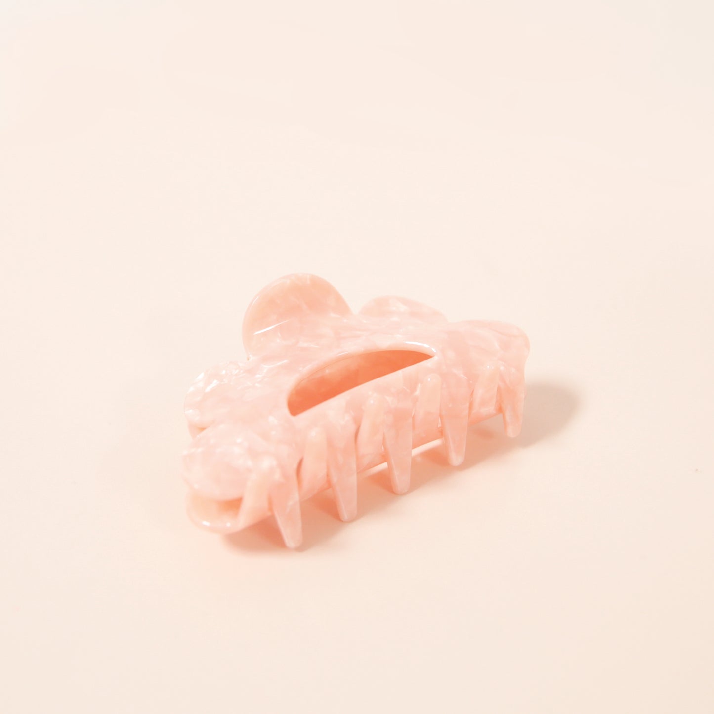 A scalloped peach hair clip made of durable plastic.