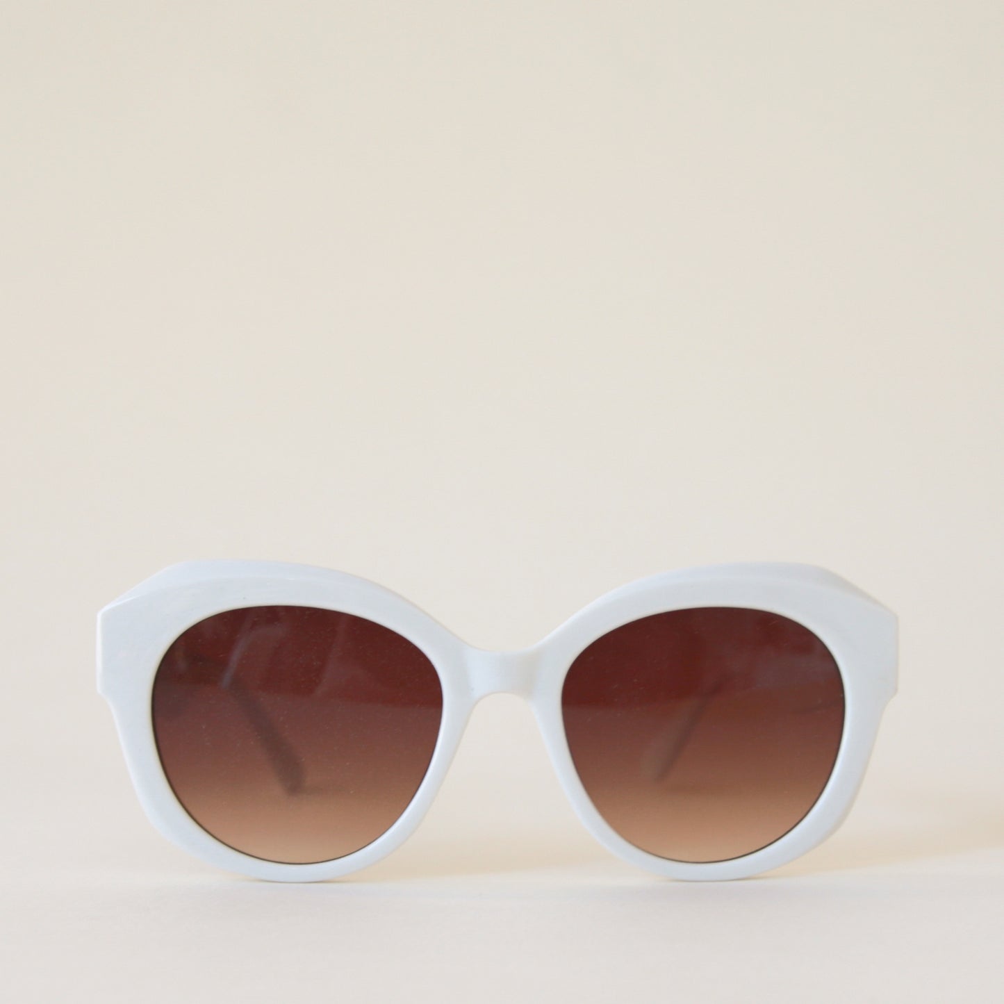 White rounded chunky sunglasses with a brown lens.