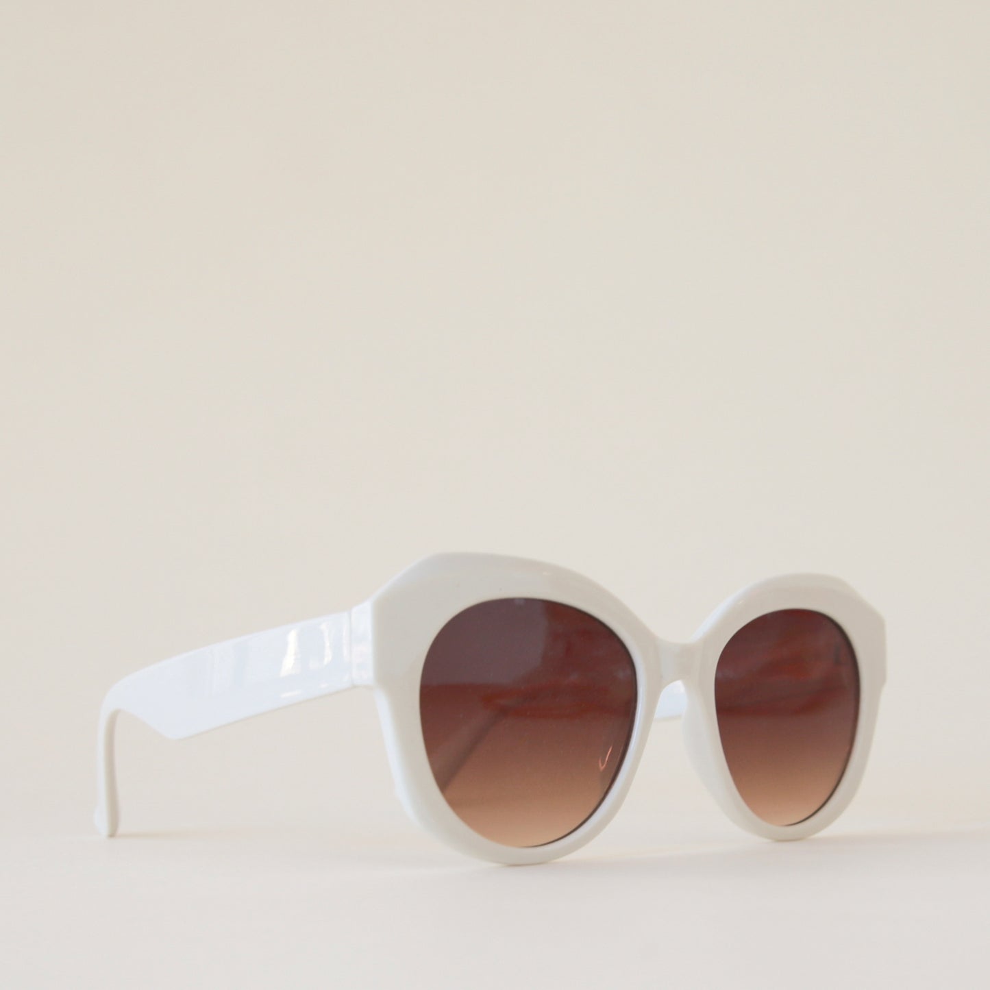 White rounded chunky sunglasses with a brown lens.