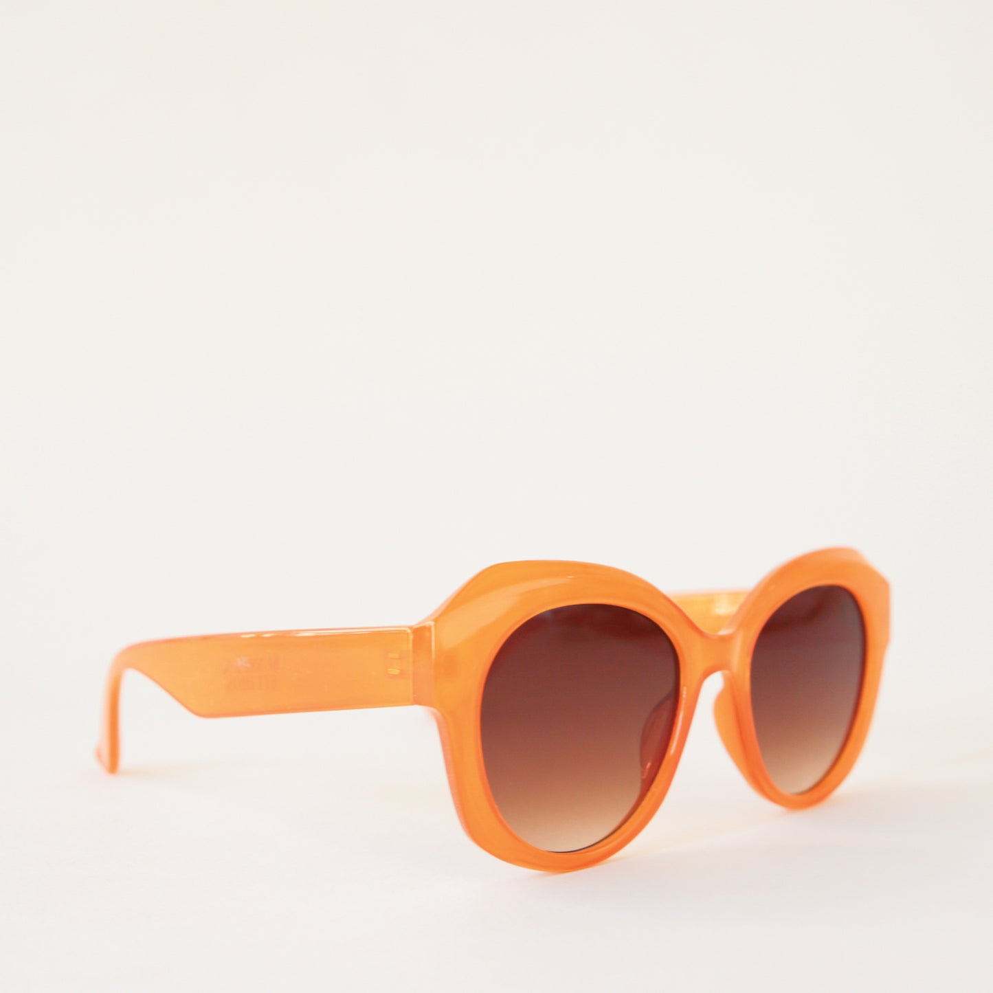 Chunky round orange sunglasses with a brown lens.