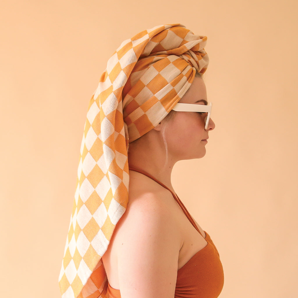 side profile view of a woman wearing a yellow checkered towel on her head