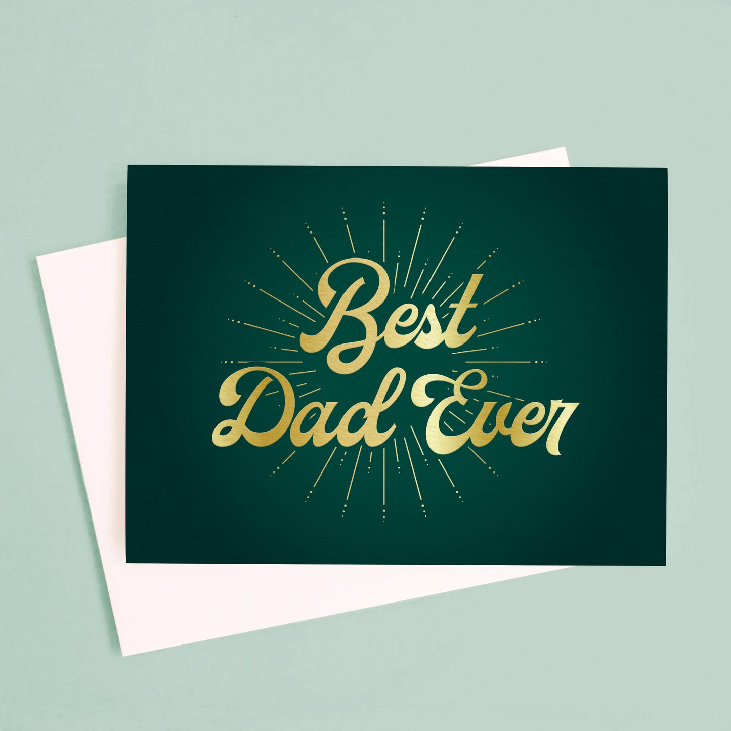 On a light green background is a dark green Father's Day card with gold text across the front that reads, "Best Dad Ever". 