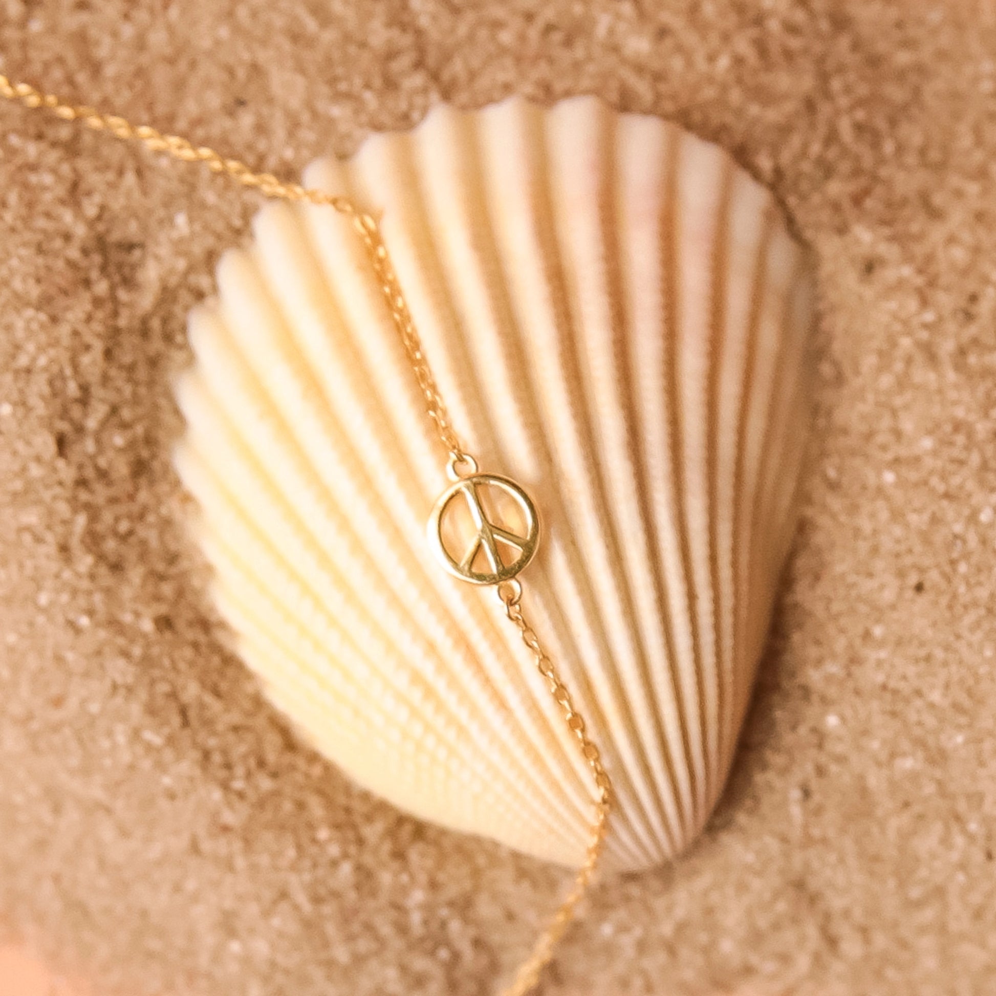 Gold chain necklace complete with classic peace sign symbol pendant. The pendent is connected to the chain by two loops on each side.