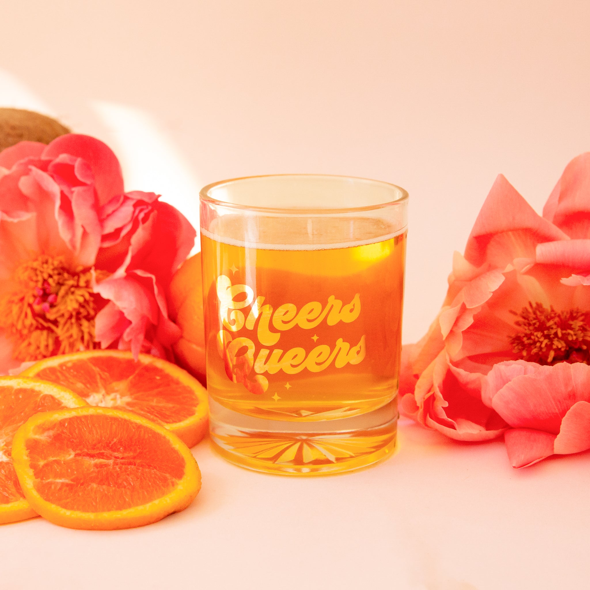 A clear glass tumbler with gold text that reads, 'Cheers Queers'.