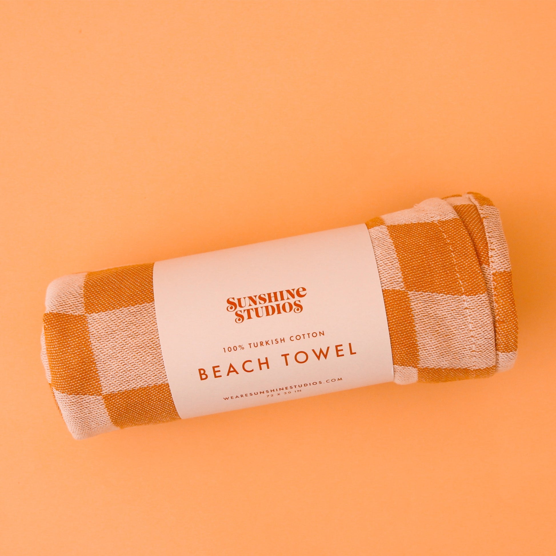 On a tan background is an orange and and light orange beach towel.