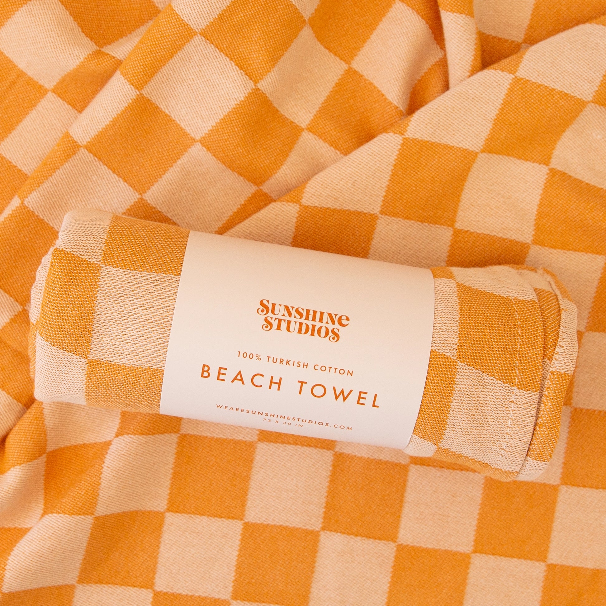 On a tan background is an orange and and light orange beach towel.