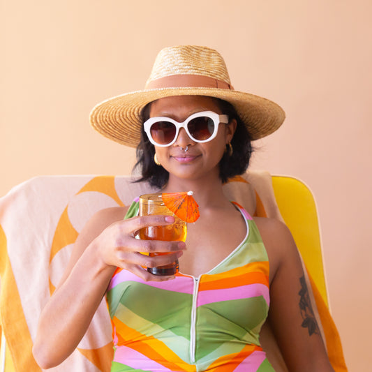 A model wearing a pair of white rounded chunky sunglasses with a brown lens.