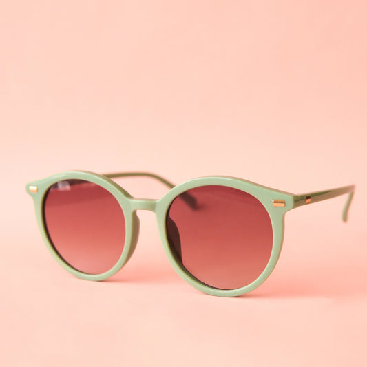 On a peach background is a light green pair of round sunglasses with a brown lens.