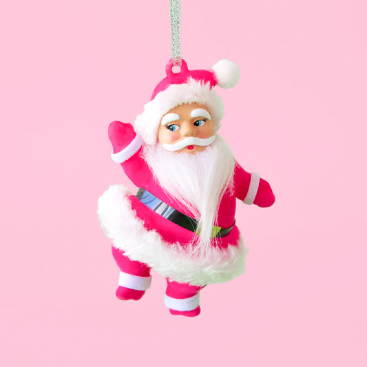 Pink flocked dancing Santa ornament against a pink background with fake snow below his feet