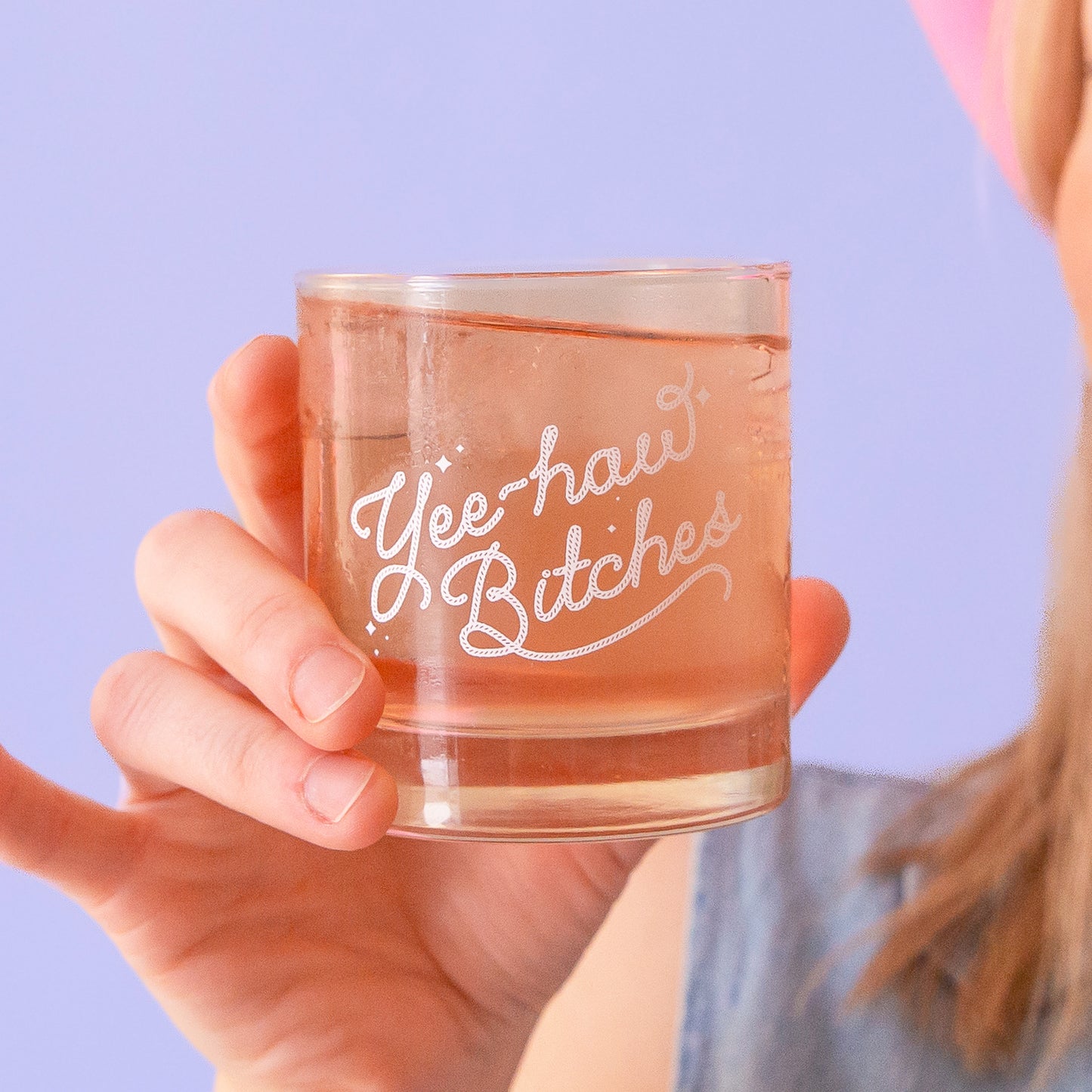 A short glass tumbler with white screenprinted text that reads, "Yee-haw Bitches".
