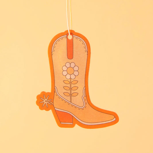 An orange cowboy boot shaped air freshener with a white string for hanging. 