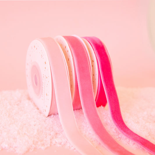 On a pink background is a pack of three pink velvet ribbon spools. 